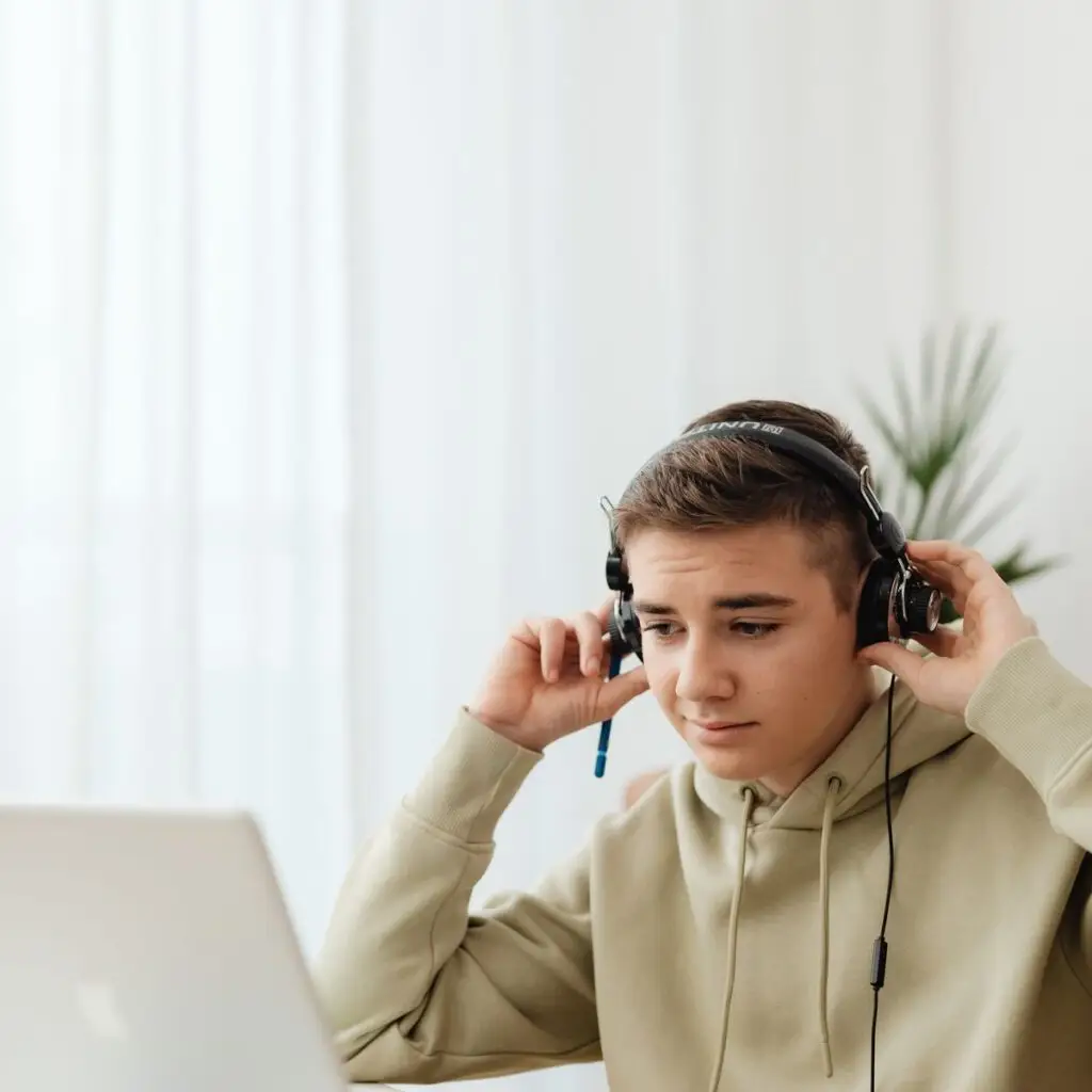 Boy using a laptop with headphones for an online Quran lesson after school